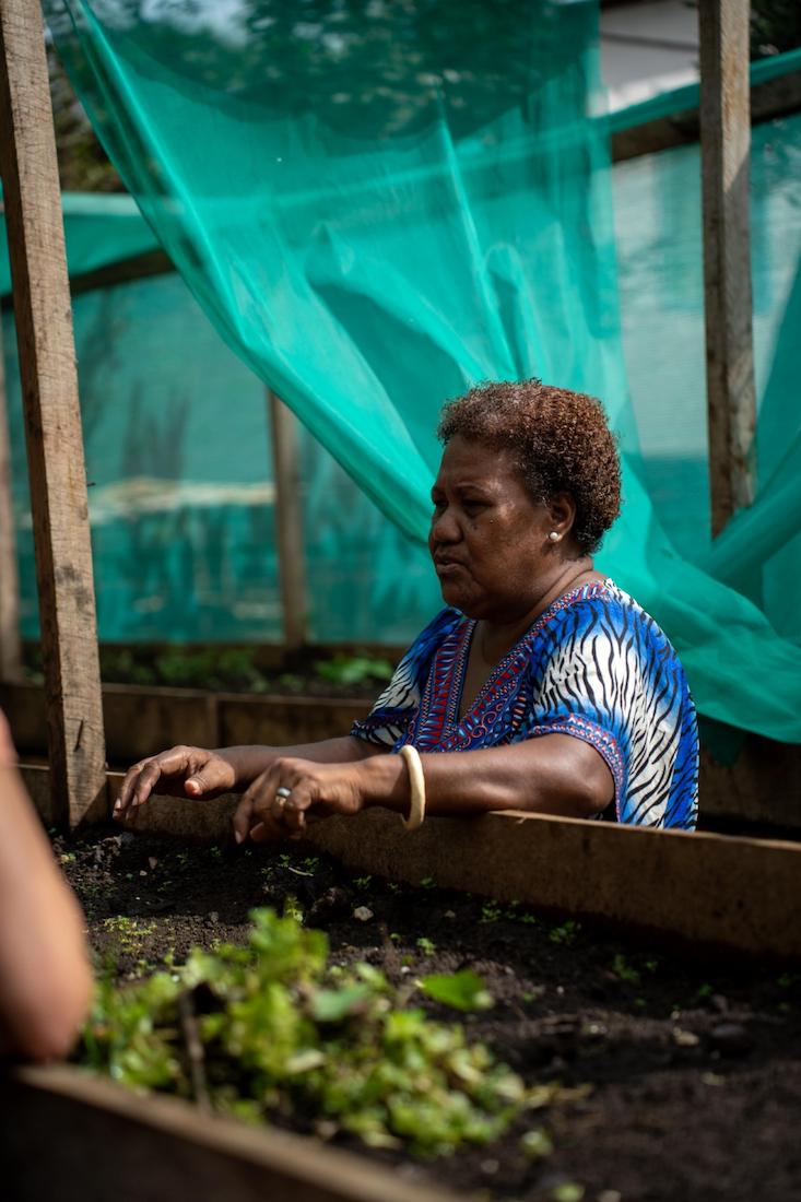 Woman standing next to a garden bed.