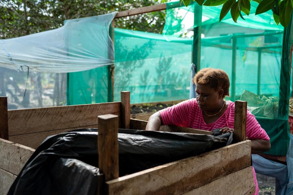 Woman tending to the garden compost bin.